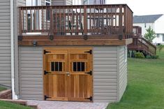 a garage with a wooden door and balcony on the top floor next to a brick walkway