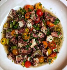 a white bowl filled with octopus and tomatoes