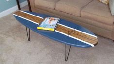 a blue surfboard sitting on top of a wooden table in front of a couch