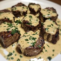 a white plate topped with steak covered in gravy and garnished with parsley