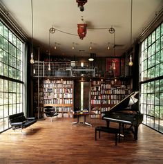 a large room with lots of windows and a piano in the center, surrounded by bookshelves