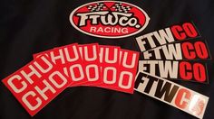 three racing stickers sitting on top of a black shirt with red and white letters