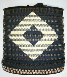 a black and white woven basket with an intricate design on the front, hanging from a hook