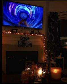 a flat screen tv sitting above a fireplace with candles on the mantel below it