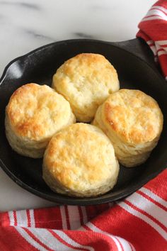 biscuits in a cast iron skillet on a red and white towel