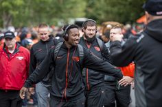 a group of men walking down a street next to each other wearing headphones and carrying backpacks