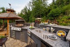 an outdoor kitchen with granite counter tops and stainless steel appliances