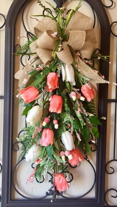 a wreath hanging on the side of a wall with flowers and greenery attached to it