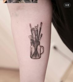 a person with a tattoo on their arm has a jar filled with pencils and scissors