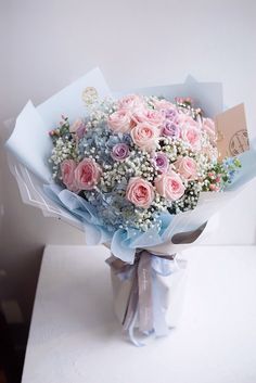 a bouquet of pink and white flowers sitting on top of a table next to a card