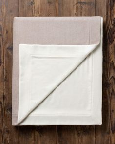 a white blanket folded on top of a wooden floor next to a piece of cloth