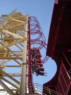 the roller coaster is red and yellow with people on it, as seen from below