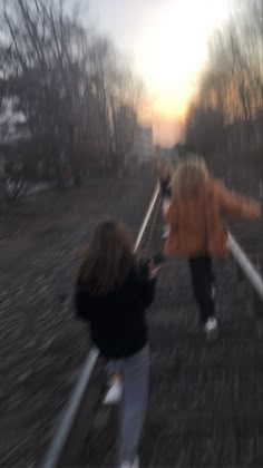 two people are walking up some stairs in the sun setting behind them and one person is holding on to railings