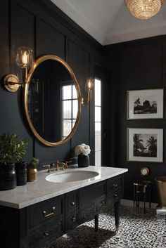 a bathroom with black walls and gold accents, including a round mirror above the sink