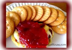 a plate with some crackers and a cheeseburger covered in ketchup