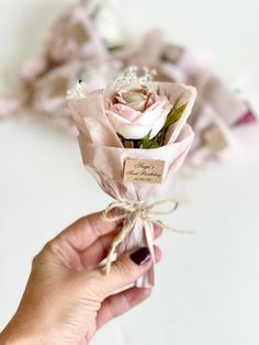 a person holding a bouquet of pink roses in their left hand and tied with twine