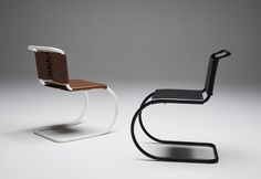 two modern chairs sitting next to each other on a white surface, one with a brown seat and the other black