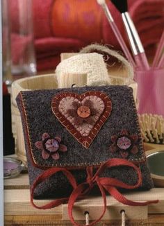 a small purse sitting on top of a table next to a vase and brush holder