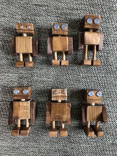 four wooden robot figurines sitting next to each other on a carpeted floor