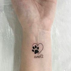 a woman's wrist with a dog paw and heart tattoo on her left arm