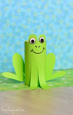 a green paper frog sitting on top of a wooden table