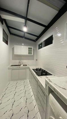 an empty kitchen with white cabinets and marble counter tops, along with black trim on the ceiling