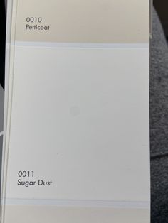 a person holding up a white paint swatch in front of their face and the words, 001 sugar dust on it