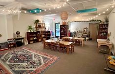 a room filled with lots of wooden tables and chairs next to a large area rug