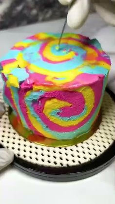 someone cutting into a colorful cake with a knife