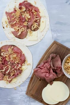 two pita breads with meat, cheese and other ingredients on a cutting board