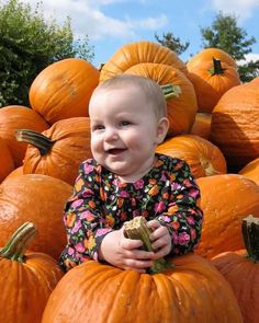 a baby sitting on top of a pile of pumpkins