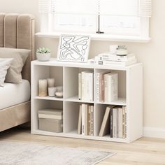 a white book shelf with books on it next to a bed