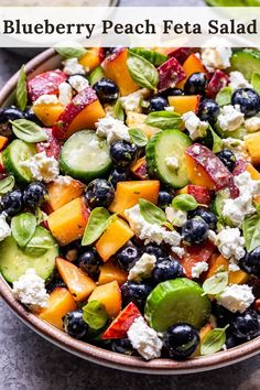 a salad with blueberries, cucumbers, and cheese