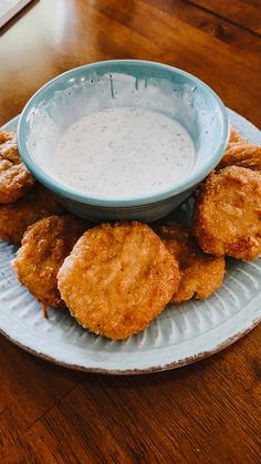 some fried food is on a plate with a bowl of ranch dressing next to it