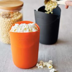 a person scooping popcorn out of an orange cup