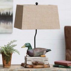 a duck lamp sitting on top of a wooden table next to a potted plant