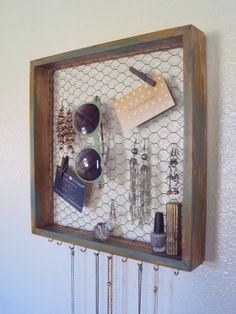 a wooden frame with sunglasses and other items hanging on the wall next to a notepad