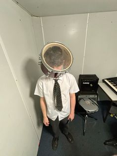 a young man wearing a suit and tie standing in front of a music equipment set