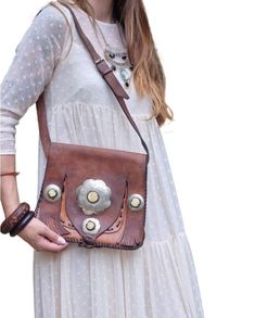 True vintage boho leather shoulder bag handmade from genuine tan brown leather. This is an old Moroccan Berber bag embellished with an engraved flower shaped metal stud and three round elements. The metal studs have been decorated with off white stones made from upcycled animal horns. It's a unique women purse with adjustable shoulder strap. It would make the perfect Western bag, festival bag or bohemian handbag for every day.  Width: 11" = 28cm Height: 10" = 25cm Shoulder strap: 15" = 38cm (adjustable) Please note that due to the age the leather is quite worn and a true piece of history. It's still a cracking bag that would make any hippie, bohemian outfit stand out. Check out my other items! I offer FREE SHIPPING on any addition items.  Check out my collection here: https://mayascuriosit Animal Horns, Festival Purse, Bohemian Handbags, Boho Shoulder Bag, Western Bag, Engraved Flower, Unique Women, Women Purse, Engraved Metal