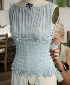 a woman looking at a dress on a mannequin