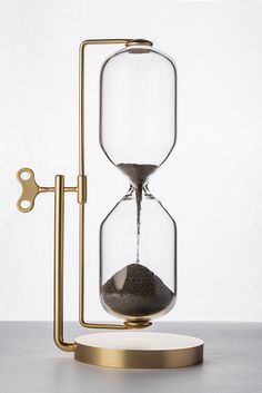 an hourglass with sand in it sitting on top of a metal stand next to a key