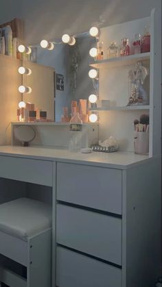 a white vanity with lights on it and a stool in front of the counter top