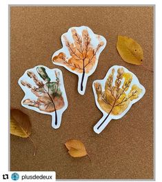 three leaf shaped stickers sitting on top of a table