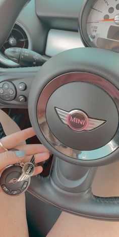 a woman sitting in the drivers seat of a car with her hand on the steering wheel