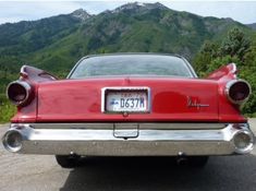 an old red car parked in front of a mountain