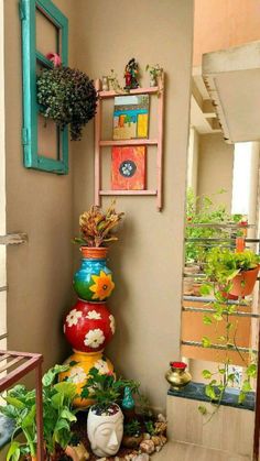 colorful pots are stacked on top of each other in front of a wall with plants