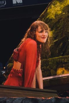 a woman in a red dress sitting on the ground