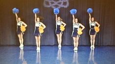 a group of cheerleaders on stage with blue pom - poms