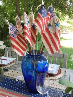 a blue vase filled with american flags sitting on top of a table next to a plate