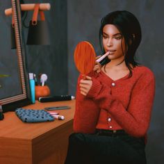 a woman is holding a wooden paddle in front of a computer desk with a mirror on it